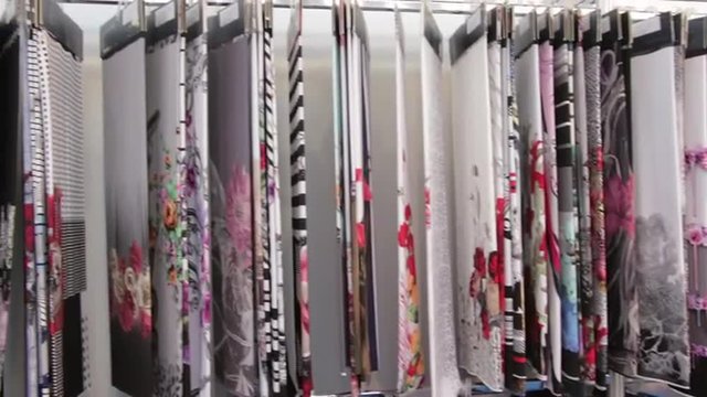 A variety of colorful fabric samples on display. Automated industrial sewing weaving knitting embroidery loom machine in textile cotton industry production fabric factory. Making clothes underwear.