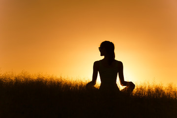 Young woman relaxing in a field. Meditation and serenity concept.