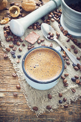 coffee in a metal mug on the old wooden background with grains
