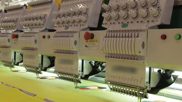 Automated Embroidery Thread Machine On Factory. Automated industrial sewing weaving knitting embroidery loom machine in textile cotton industry production fabric factory. Making clothes underwear.