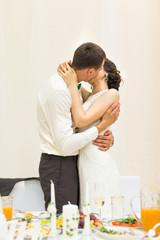 Obraz na płótnie Canvas Romantic happy handsome groom kissing beautiful white dress bride at wedding reception