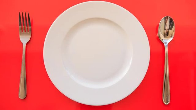 Hands Put Fork Spoon Vertically by Plate on Red Table