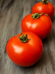 Ripe red tomatoes with green tail on a gray blue painted wooden background