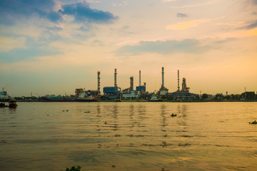 Fototapeta premium Silhouette of oil refinery factory over sunrise