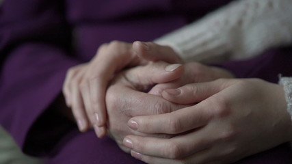 Closeup young hand comforting a old pair of hands. Slowly