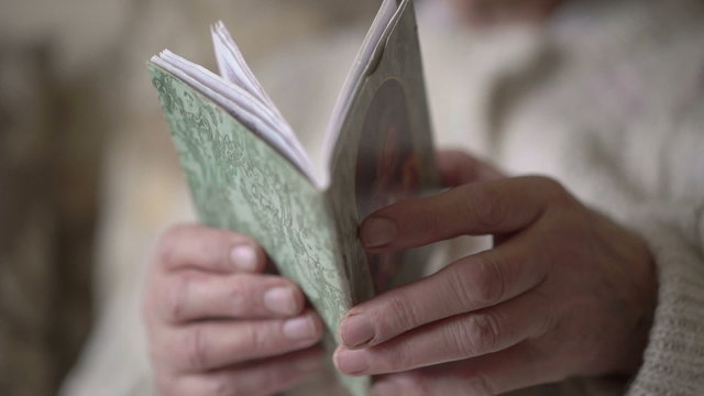 Prayer book in old woman's hands. Slowly