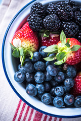 Rustic bowl full of forest summer berry fruits