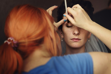 Professional stylish putting on makeup on beautiful brunette bri