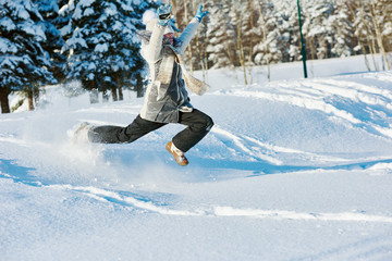 happy girl jumping into snow in winter