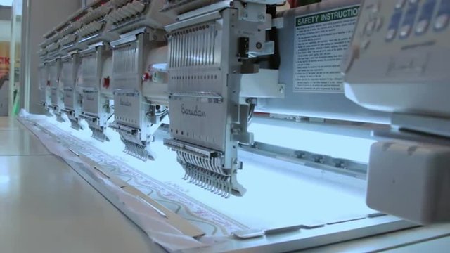 Clothing dress production in the textile industry. Automated industrial sewing weaving knitting embroidery loom machine in textile cotton industry production fabric factory. Making clothes underwear.