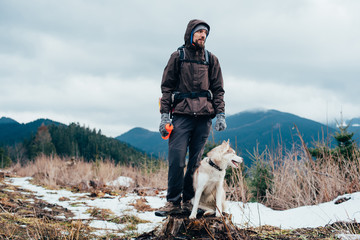 hiker with siberian husky dog looking at beautiful view in mountains