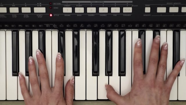Woman hands playing on synthesizer, top view close up