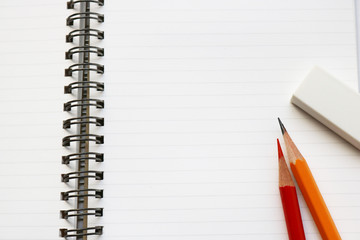 Blank notebook with pencil, red pencil, and eraser on white background.