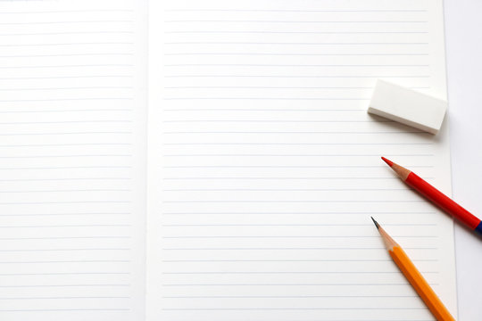 Blank notebook with pencil, red pencil, and eraser on white background.