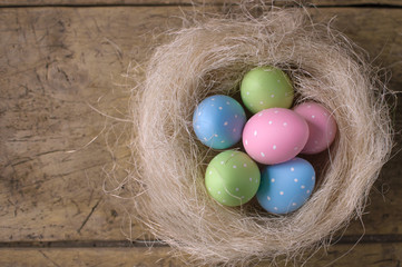 Easter eggs in nest on wooden background