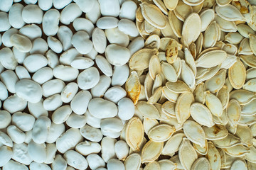 Pumpkin white seeds and white beans background. Top view.