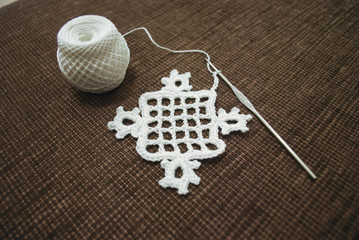 Crochet sample for tablecloth or napkin from cotton on brown background.