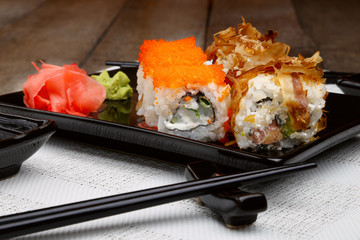 Sushi set on plate with wasabi and marinated ginger on wooden table with soy sauce