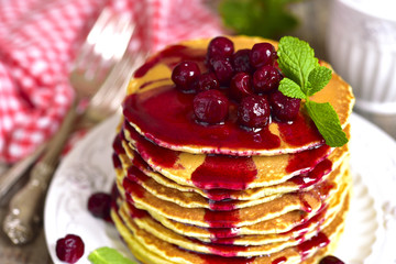 Homemade pancakes with cherry on a wooden background.
