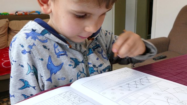 Boy of five years writing in a notebook with his left hand.