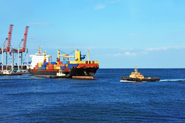 Tugboat assisting container cargo ship