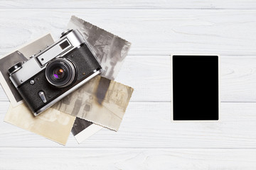 Old retro camera with empty photo on vintage wooden background.