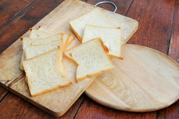 Sliced white bread and French bread baguette on wooden board
