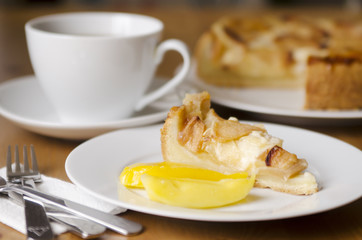 Table served to tea drinking. White cup of tea, paper napkin, cutlery and apple homemade pei  on the wooden table.