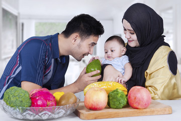 Fototapeta na wymiar Arabian father giving fruit to his baby