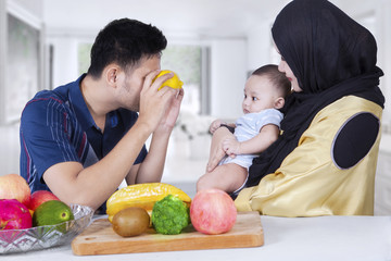 Dad playing with his baby using orange fruits