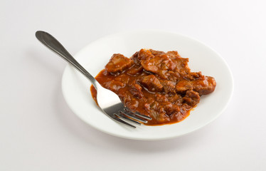 Braised beef on a plate with fork atop table cloth