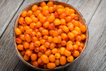 Buckthorn berry basket on wooden background.