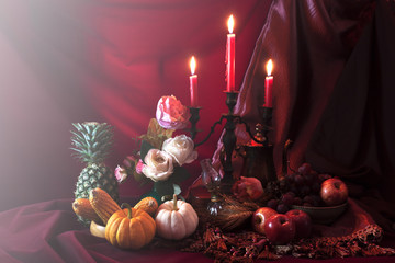 Still life with grape,apple pineapple and pumpkin with candle st