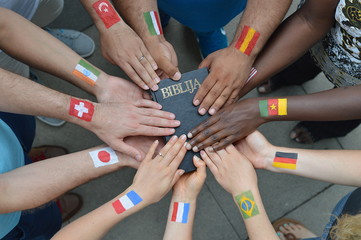 Internationale Brüder und Schwestern in Christus mit unterschiedlichen Flaggen auf ihren Armen...