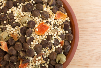 Top close view of quinoa and lentil dry soup mix in a small bowl atop a wood table top.