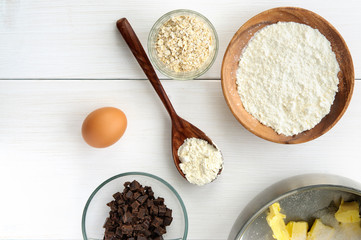 Food ingredients and kitchen utensils for cooking oat cookies on white wooden background. Top flat view