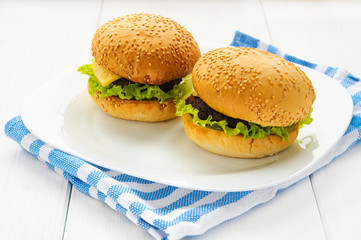 Home made beef burgers on plate and napkin. White wooden background
