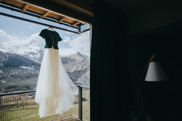 Vintage wedding dress hanging on a balcony on a background of sn