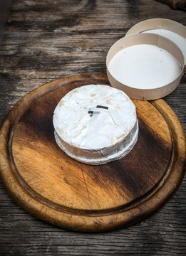 Whole camembert cheese rustic wooden cutting board