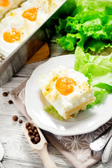 
breakfast or lunch , air , beaten egg and baked in the oven , with lettuce and herbs on a white wooden background