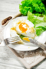 
breakfast or lunch , air , beaten egg and baked in the oven , with lettuce and herbs on a white wooden background