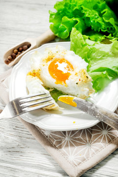 
breakfast or lunch , air , beaten egg and baked in the oven , with lettuce and herbs on a white wooden background