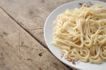 Spaghetti in a white bowl on a wooden surface