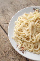 Spaghetti in a white bowl on a wooden surface