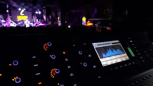 Audio mixer console in live consert with show on background