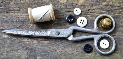 Vintage Background with sewing tools.Sewing kit. Scissors,buttons, bobbin with thread and thimble on the old wooden background