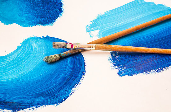 Brushes On A Paper With A Blue Drawing