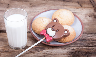 Chocolate sweet bear, chip cookies, milk, wood background