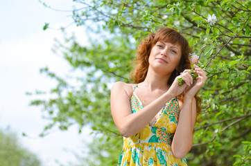 young beautiful girl walks in the spring green apple orchard