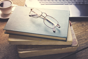 glasses on books, coffee and computer on table